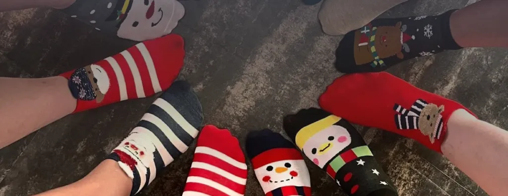 Füße in bunten weihnachtlichen Socken im Kreis zusammengestreckt