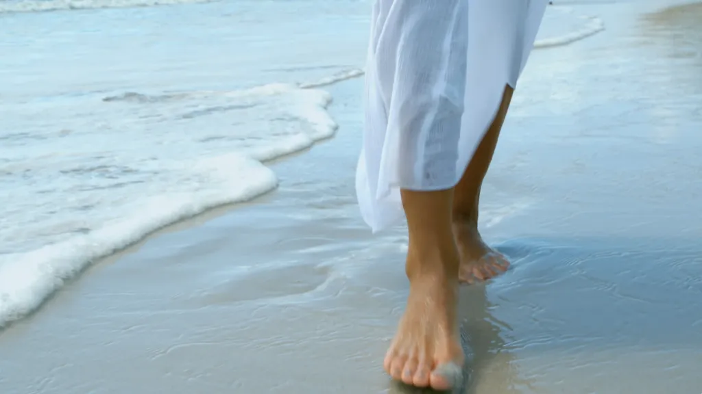 Barfuß am Strand durch seichtes Wasser laufen
